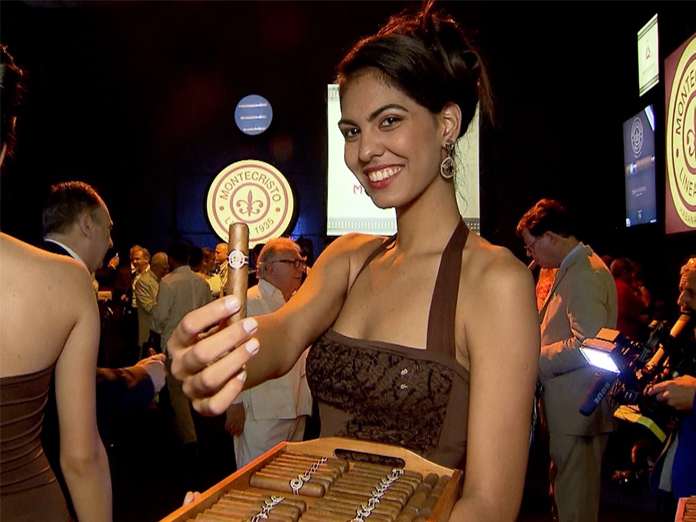 Two men shaking hands and smiling at a cigar and bourbon event under a white tent